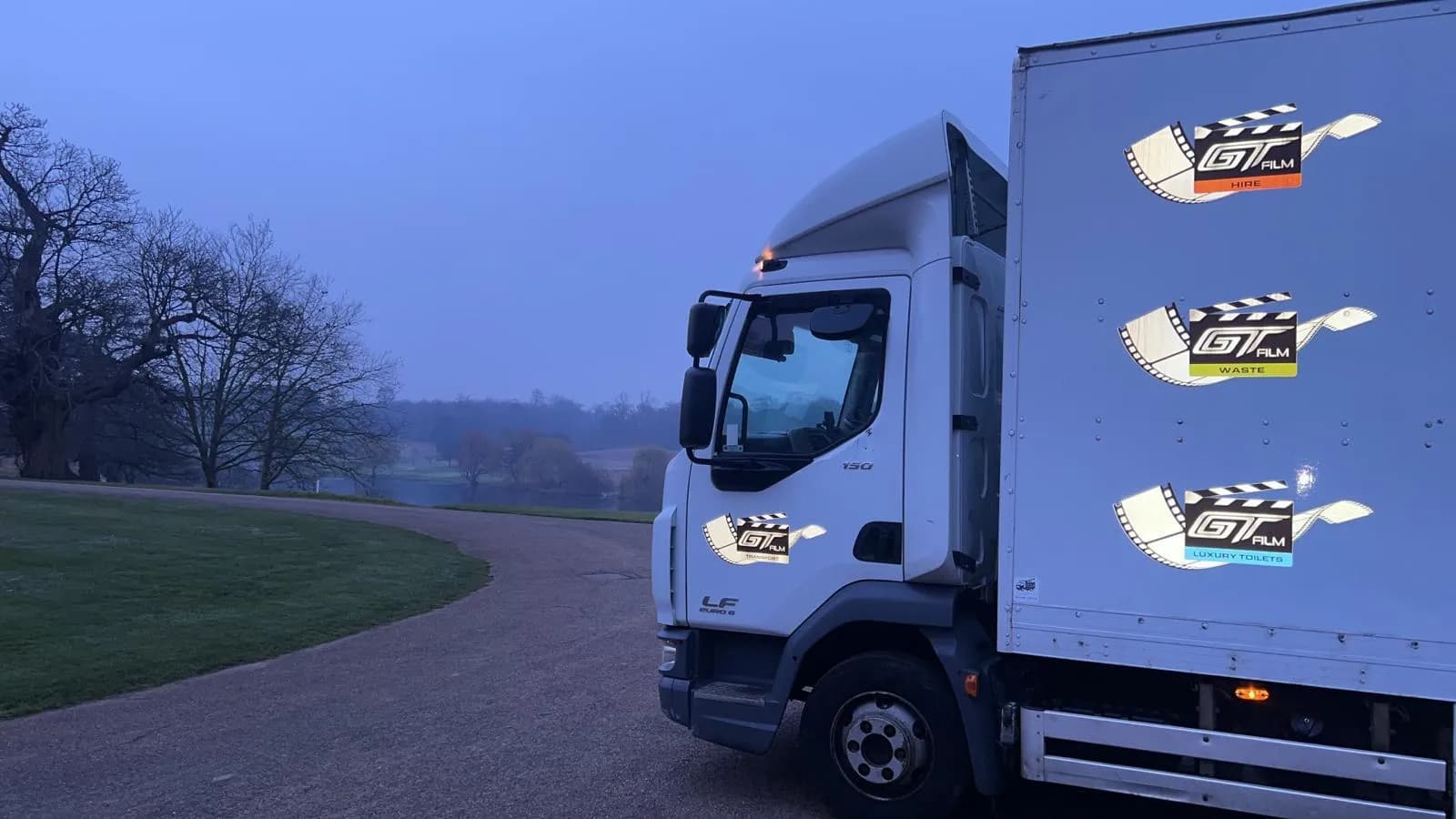 A white truck parked on top of a dirt road.