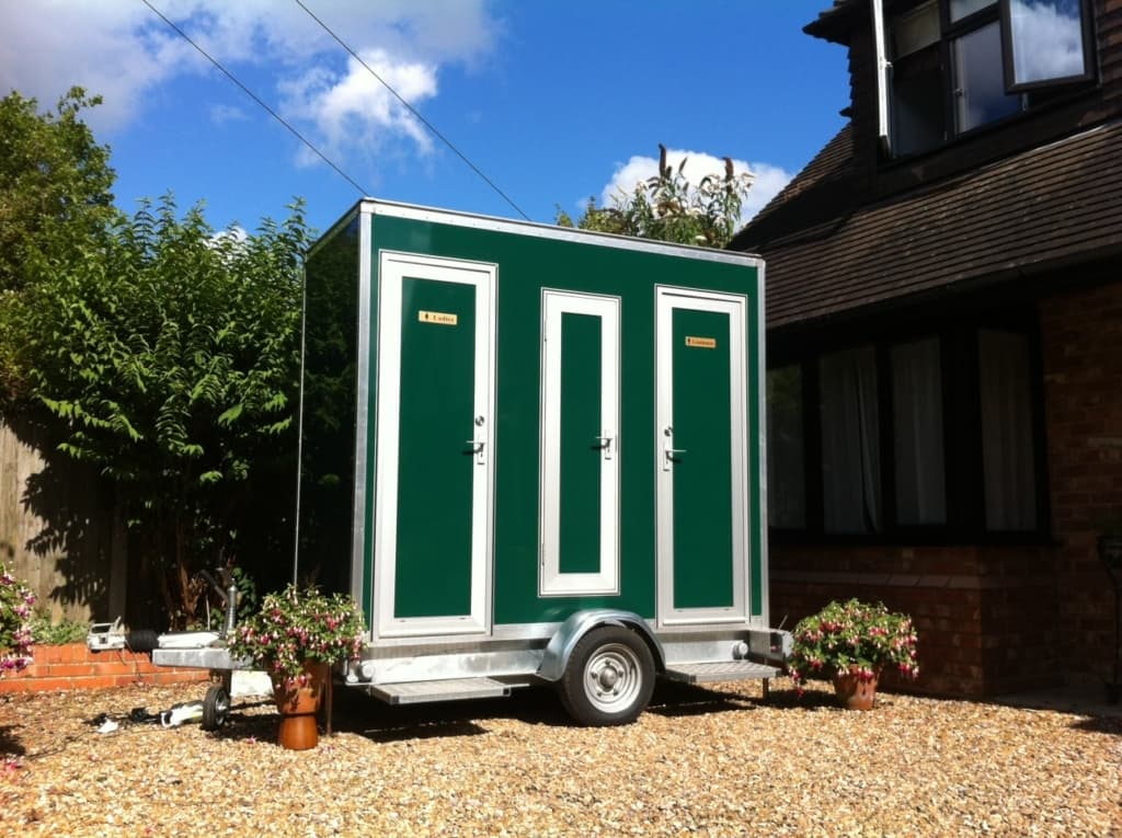 Compact 1 plus 1 Deluxe Loo luxury toilet trailer parked on gravel driveway